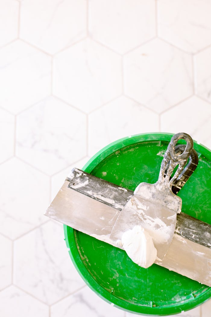 about-03 Close-up of a trowel and putty on a green bucket, ideal for renovation projects.